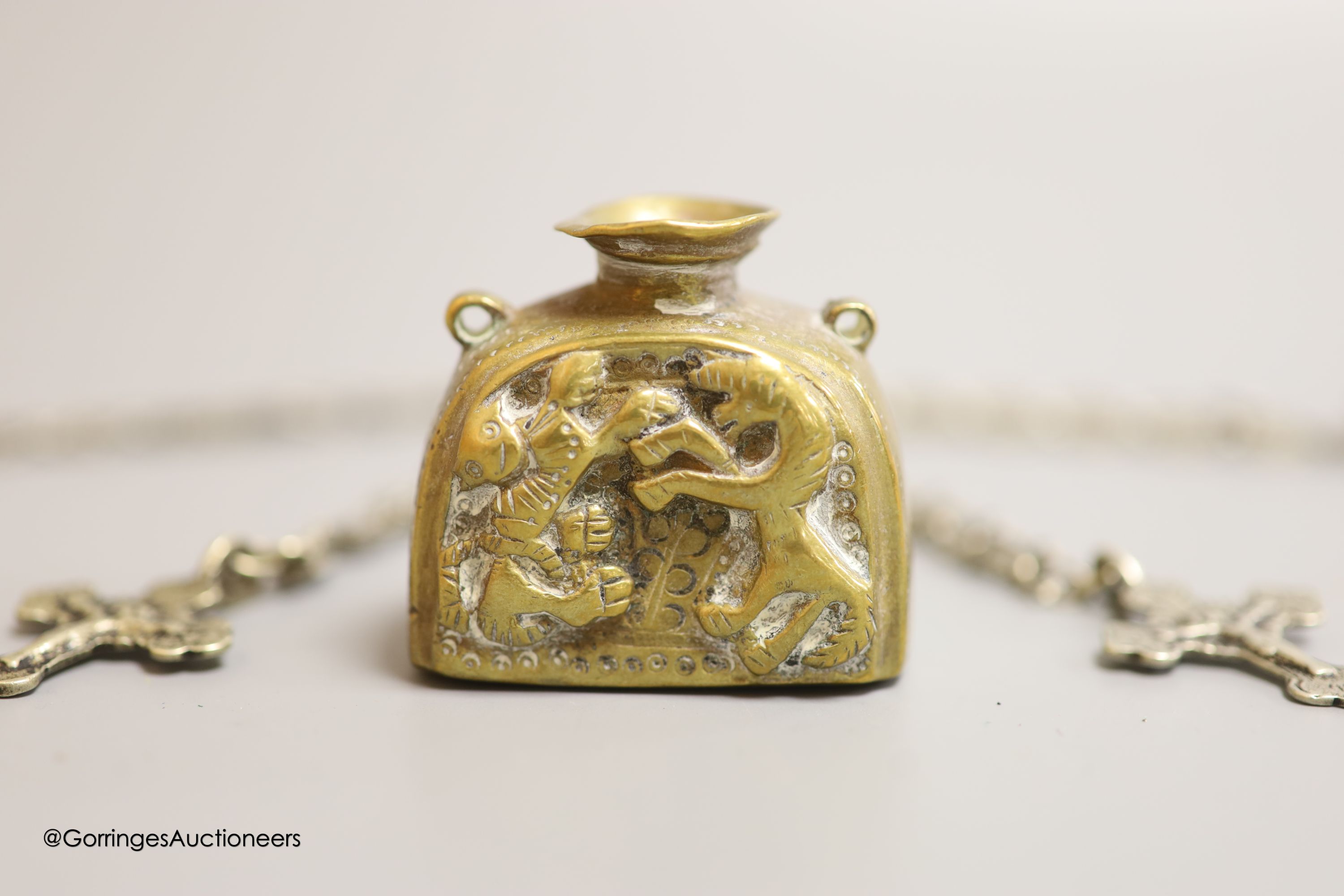 Two Russian white metal crucifixes on pierced oval link neck chains and a cast brass scribes ink pot.